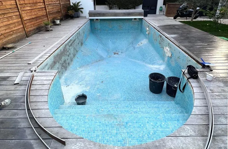 Avant : bassin en mosaïque abîmée, vidé, avec des seaux de chantier